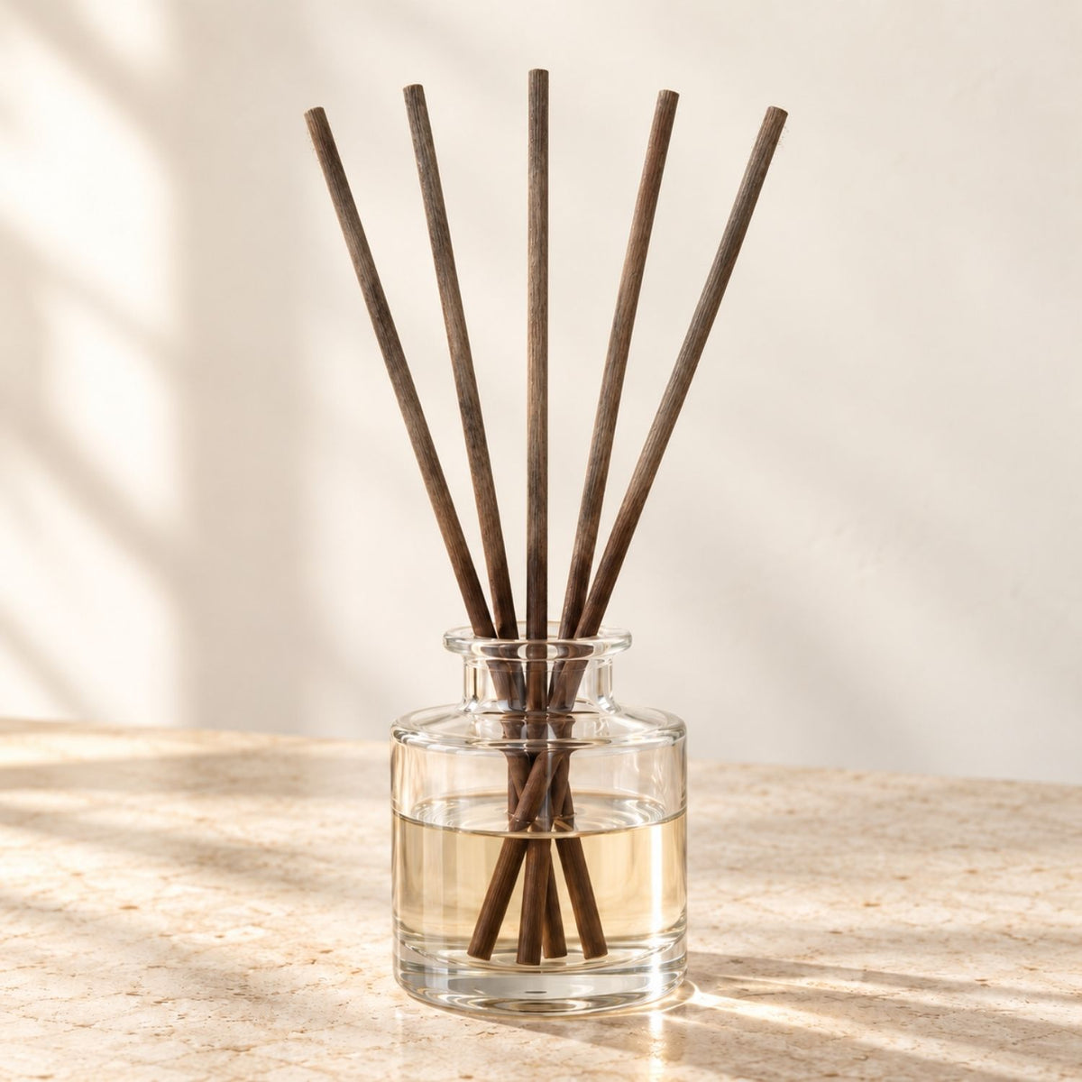 Five existing used diffuser reeds in a clear-glass vessel