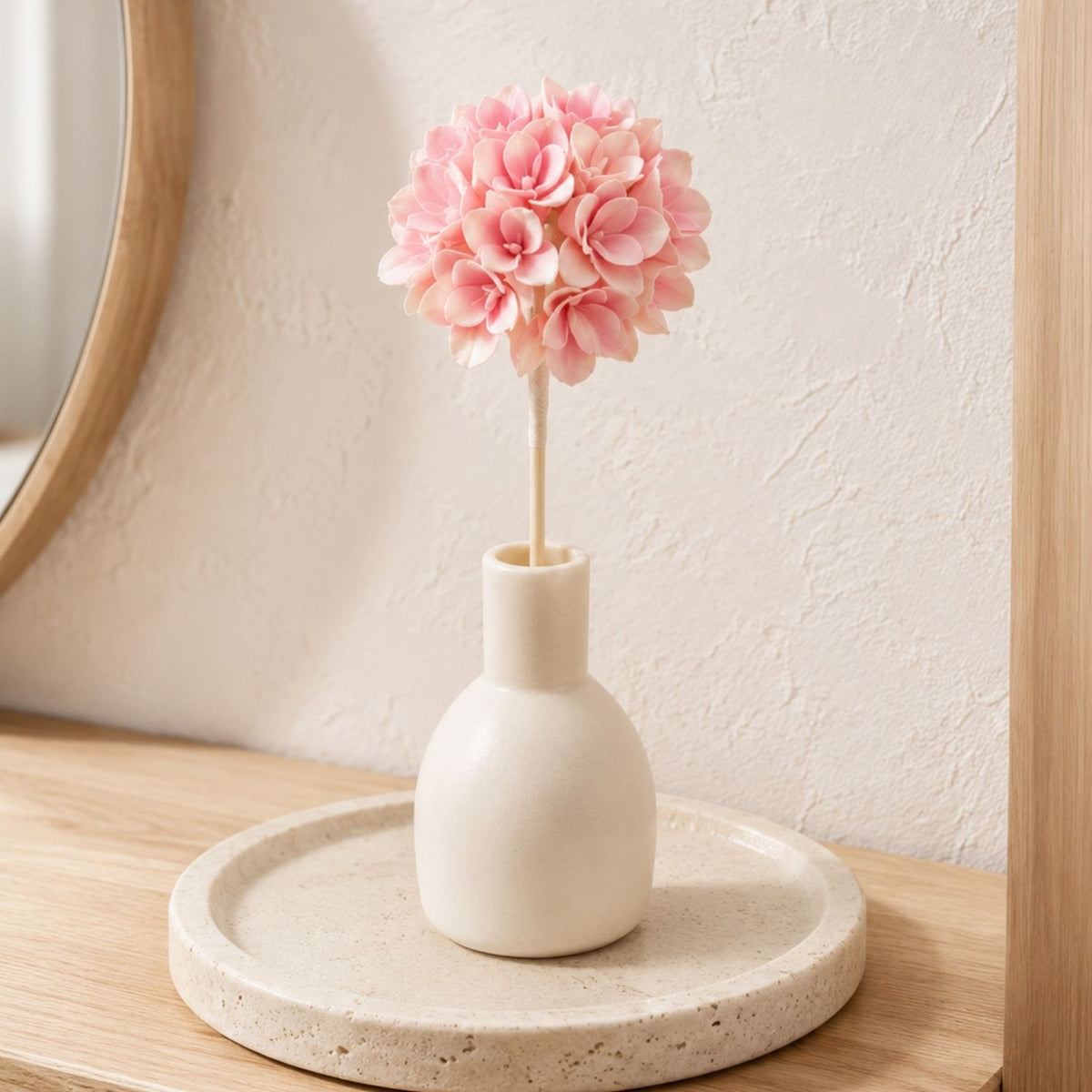 Hanazora Momoiro Blush Pink flower-ball reed styled in an ivory vessel on a light-oak vanity.